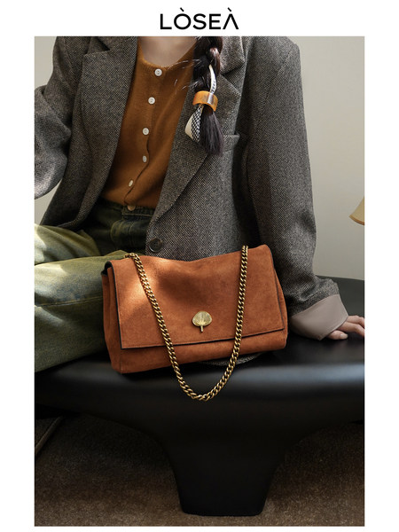 Brown suede chain-strap shoulder bag worn by a model