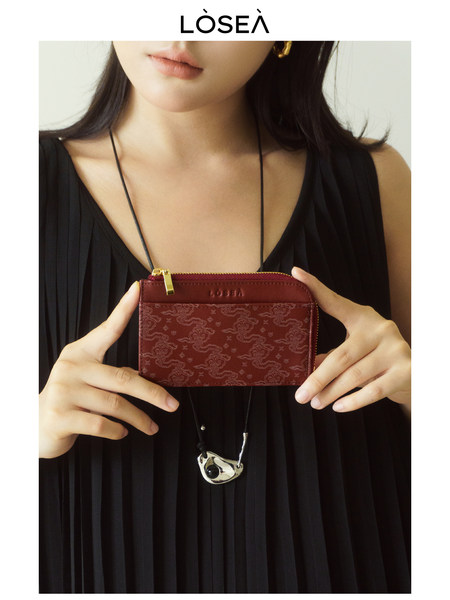 Model holding a burgundy patterned small wallet or mini pouch
