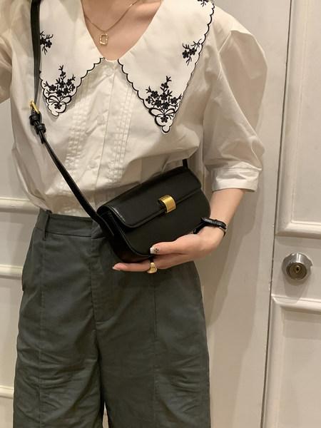 Woman wearing a white embroidered blouse with a black crossbody bag