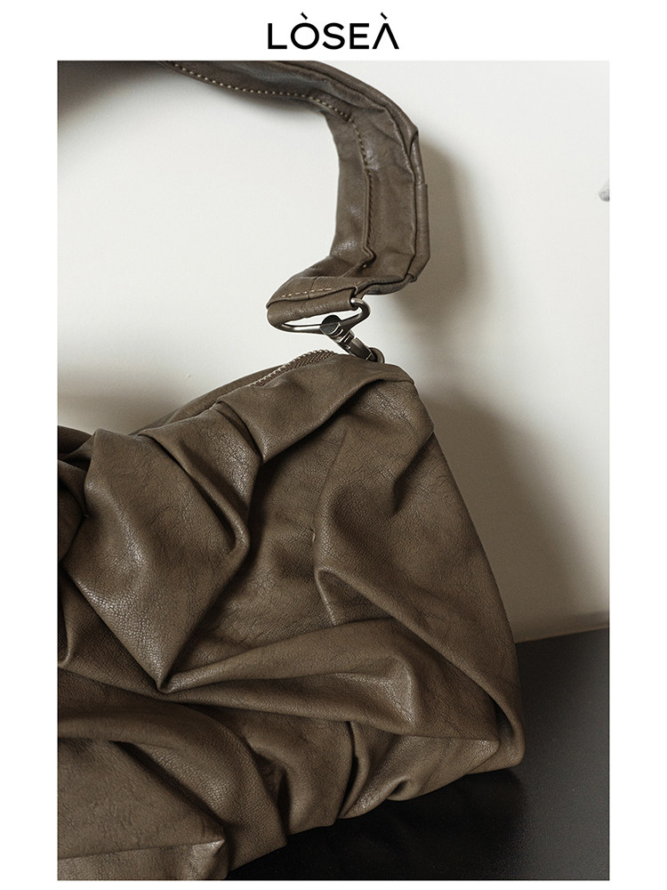 Brown leather shoulder handbag on a plain background