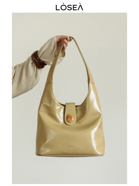 Beige glossy shoulder handbag with a top handle and button closure