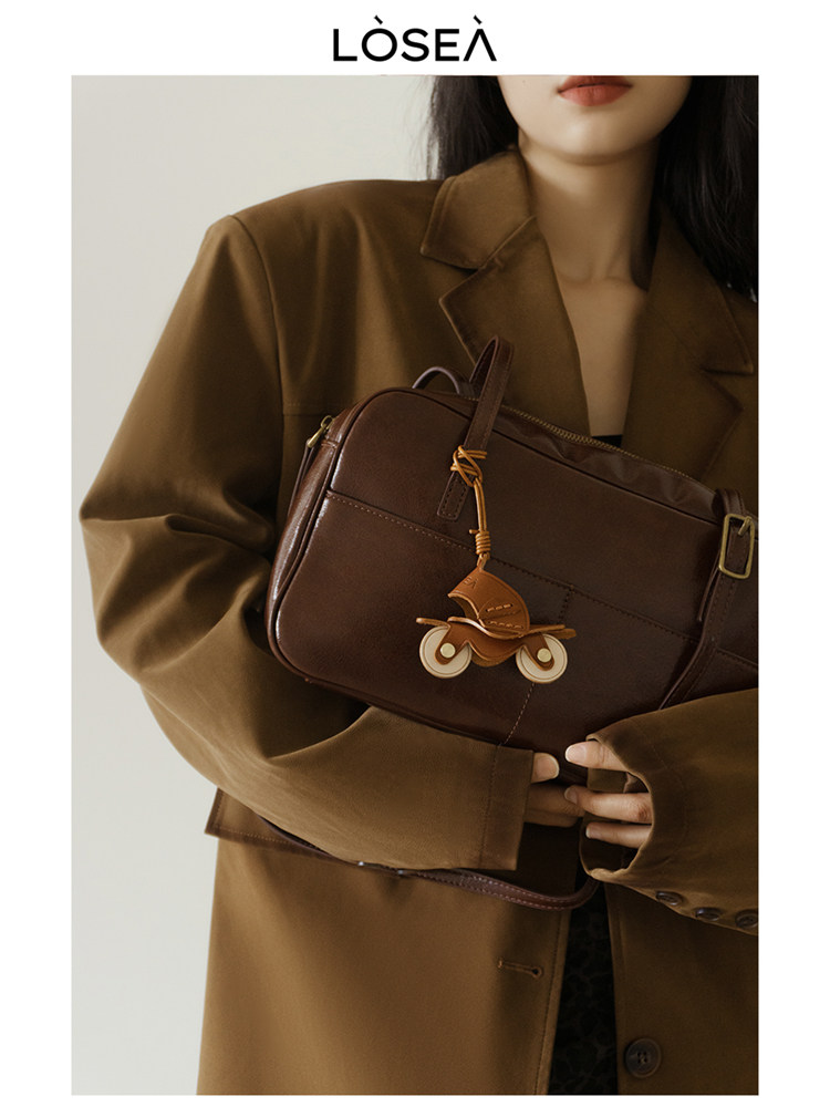 Brown leather handbag worn by a model in a brown blazer