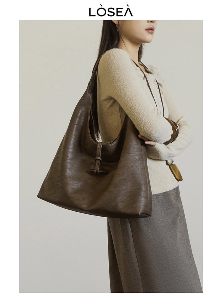 Brown leather tote bag worn by a model