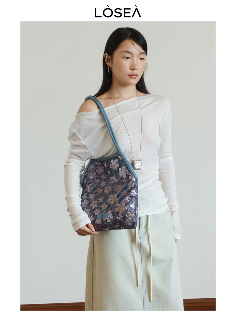 Model wearing a floral shoulder bag with a white top and light skirt
