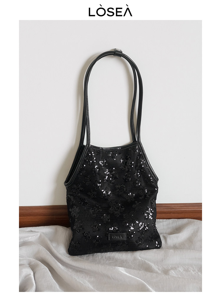 Black sequin handbag with long shoulder straps on a white background