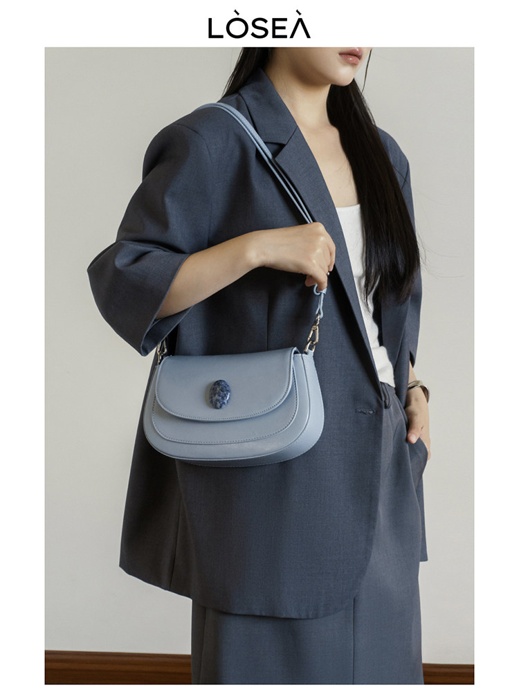 Light blue shoulder handbag worn with a dark suit on a model