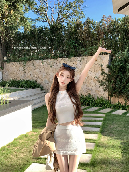 Woman wearing a white sleeveless crop top and matching skirt outdoors