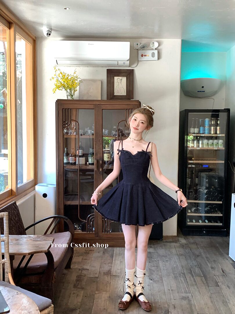Model wearing a dark sleeveless flared dress with bow straps