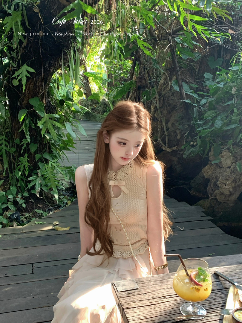 Young woman wearing a cream sleeveless dress in a lush tropical outdoor setting
