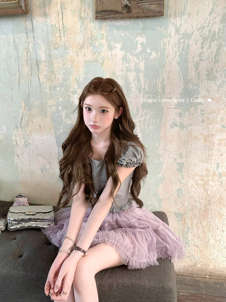 Young woman wearing a gray puff-sleeve top and lilac tulle skirt