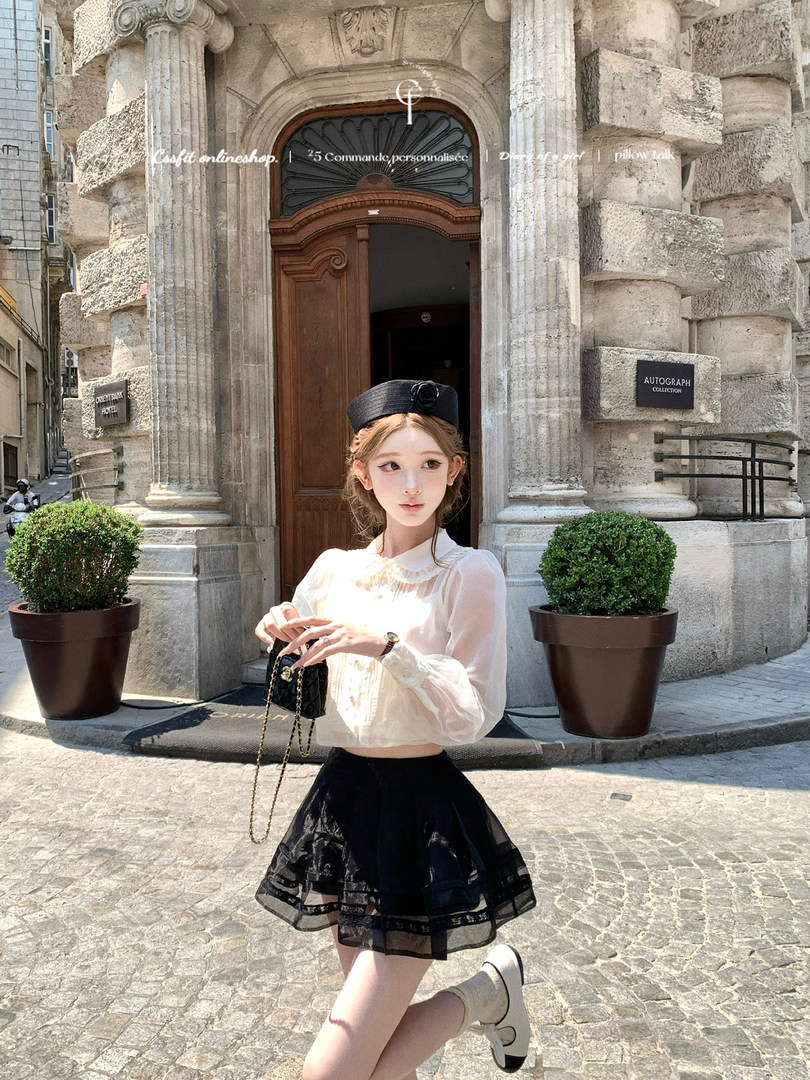 Young woman wearing a sheer white blouse and black skirt with a small black handbag outdoors