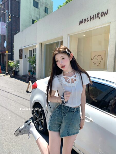 Woman wearing a white ruffled crop top and denim shorts outdoors