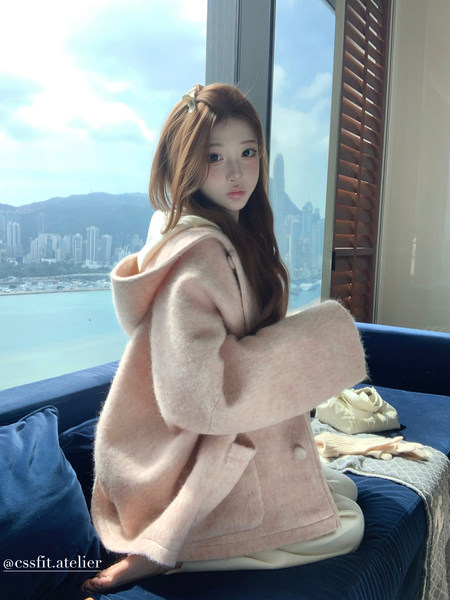 Model wearing a soft pink hooded coat indoors