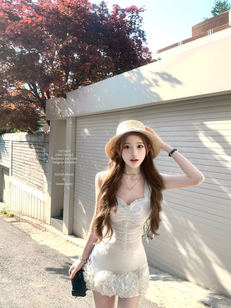 Woman wearing a white ruched mini dress and straw hat outdoors