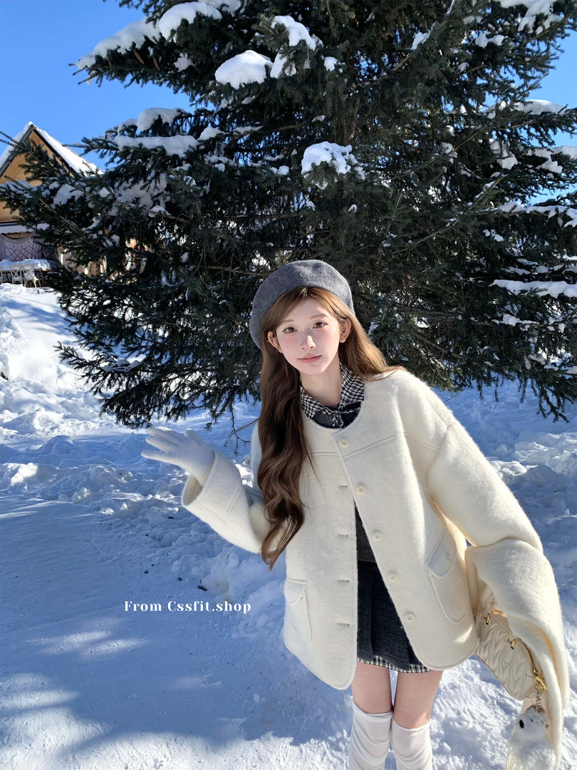 Woman wearing a cream winter coat and beret in a snowy outdoor setting