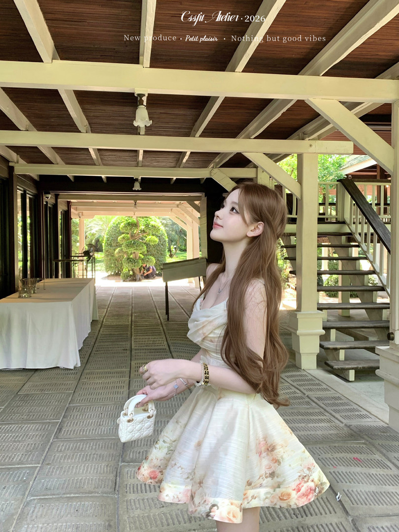 Woman wearing a white floral sleeveless dress and holding a small quilted handbag