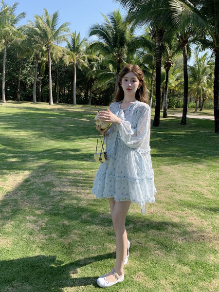 Light blue floral dress worn by a model outdoors in a tropical setting