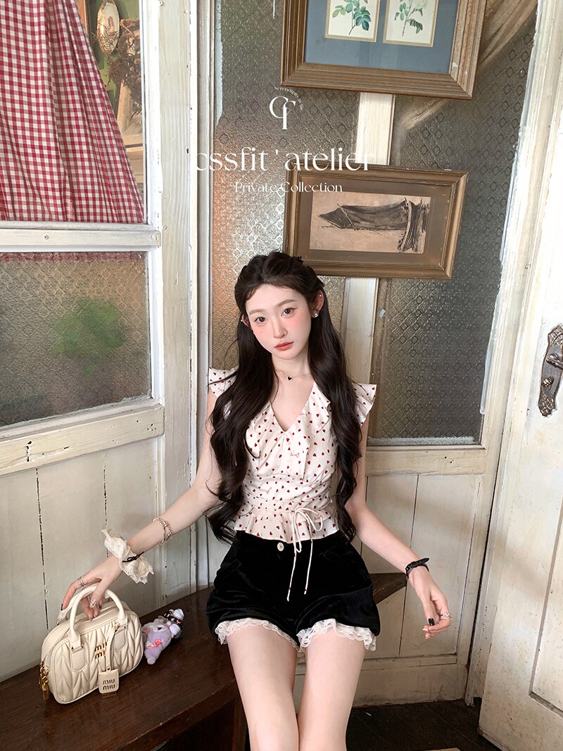Model wearing a white patterned sleeveless tie-front top with black lace-trimmed shorts