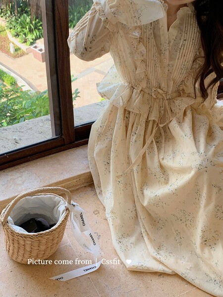 Cream floral long-sleeve dress worn by a woman indoors