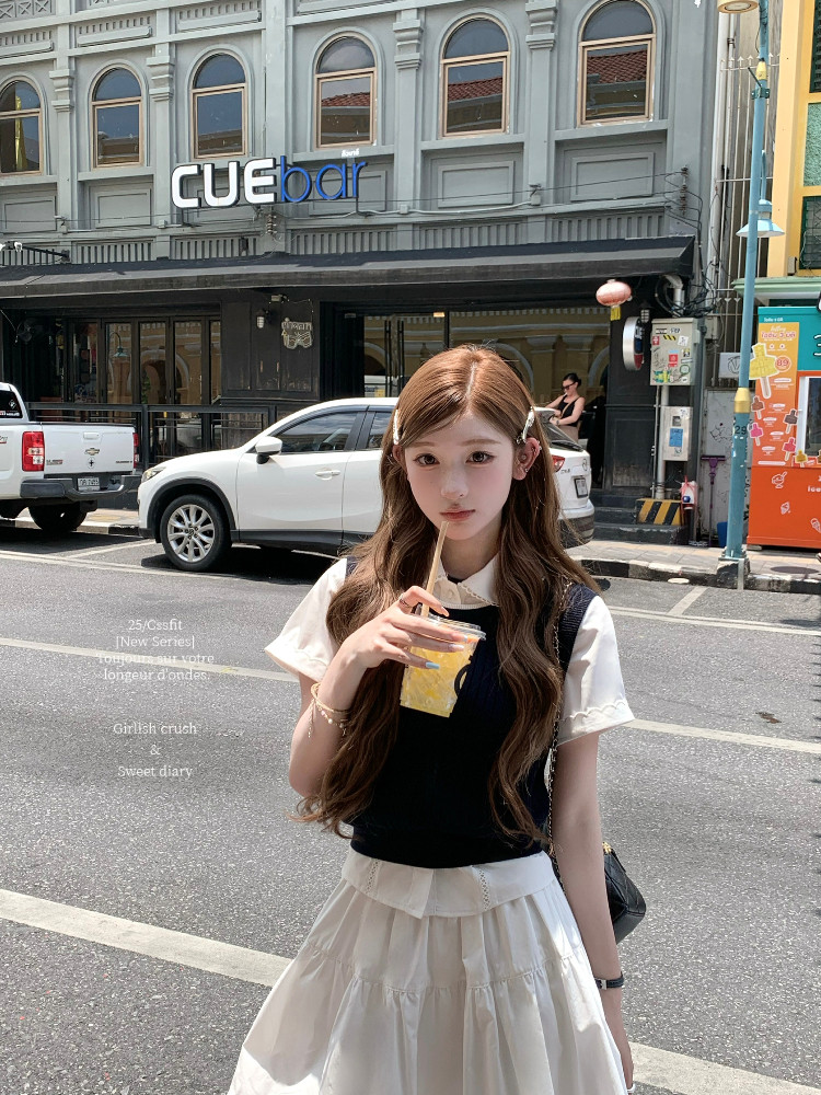 Young woman wearing a black top over a white blouse with a white skirt on a street
