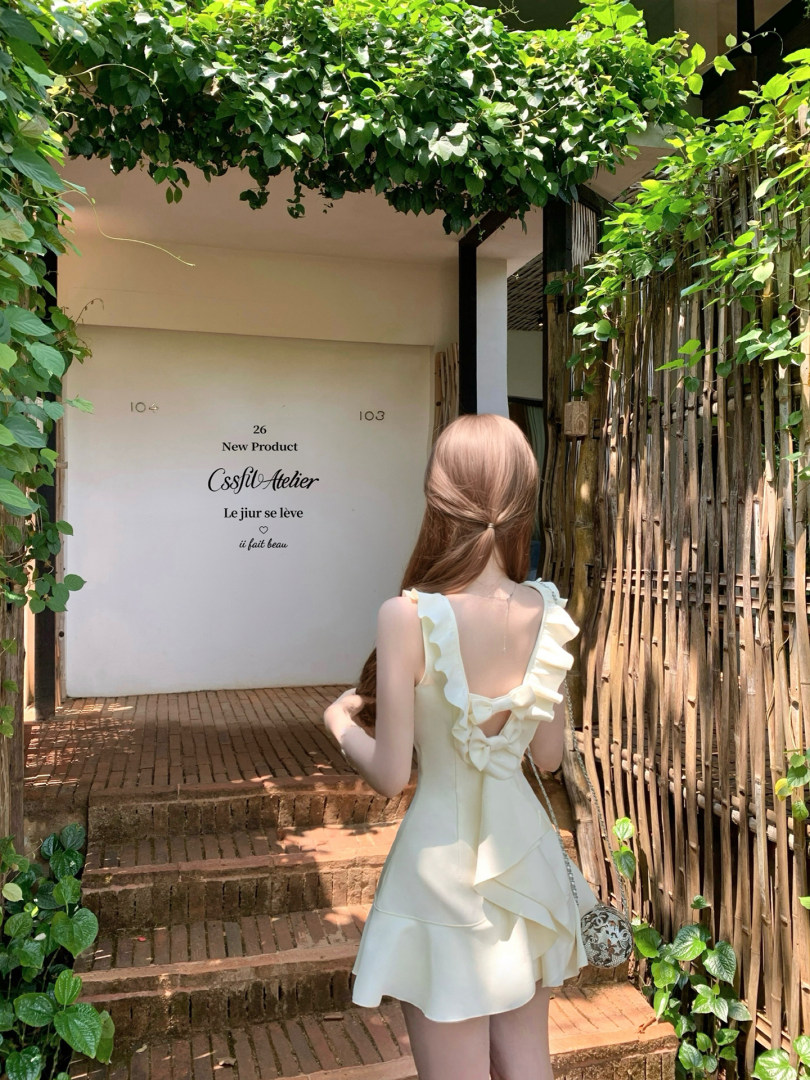 Woman wearing a cream ruffled sleeveless dress outdoors