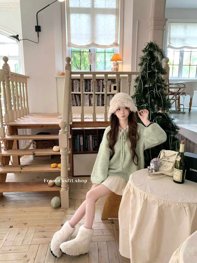 Model wearing a cozy winter outfit with fuzzy hat, sweater, mini skirt, and boots