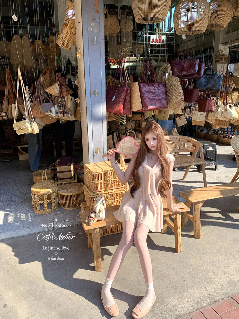 Woman wearing a light pink sleeveless dress posing in a woven bag shop