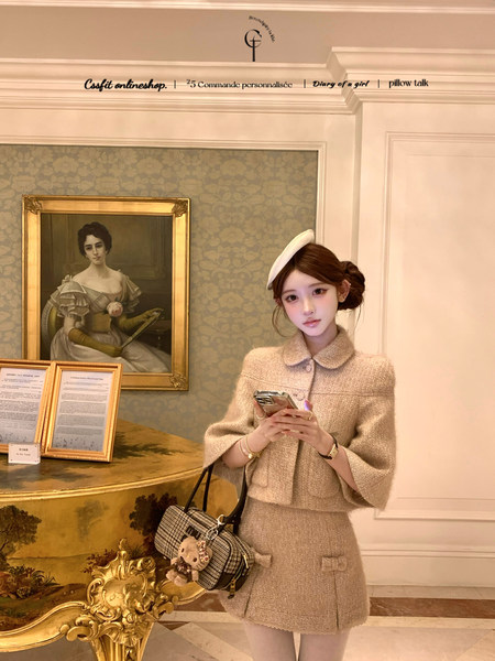 Model wearing a beige tweed jacket and skirt set with a white beret and handbag