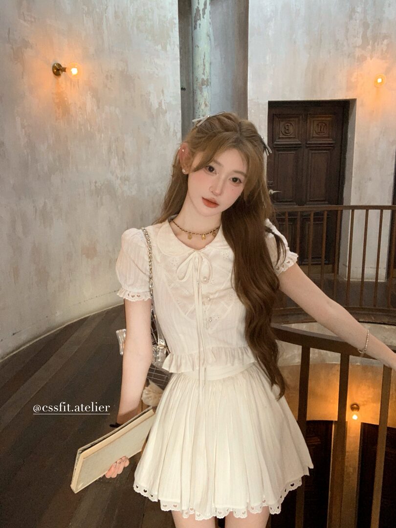 Woman wearing a white short-sleeve pleated dress with a bow detail
