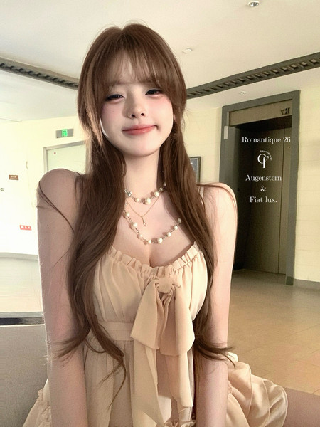 Woman wearing a beige ruffled dress with sheer sleeves and layered necklace