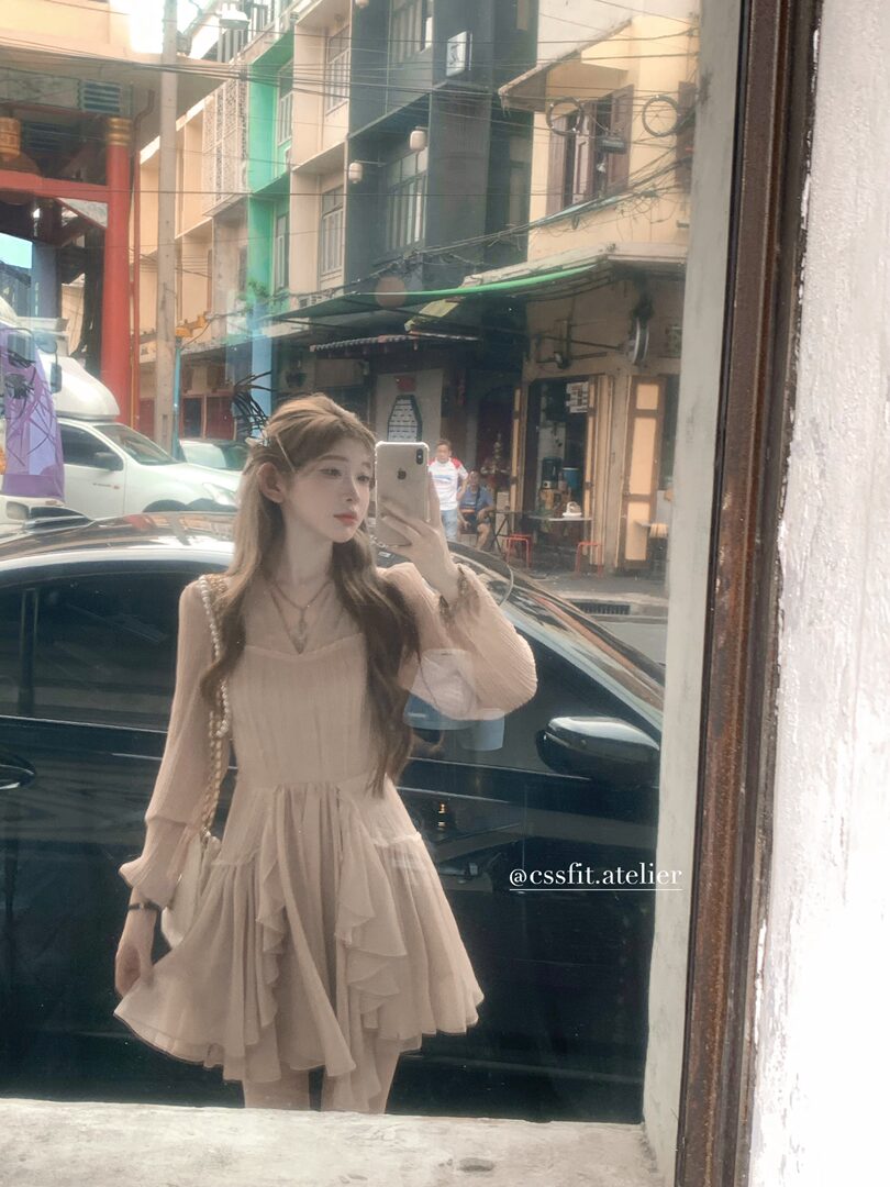 Woman wearing a light beige long-sleeve layered dress in a mirror selfie