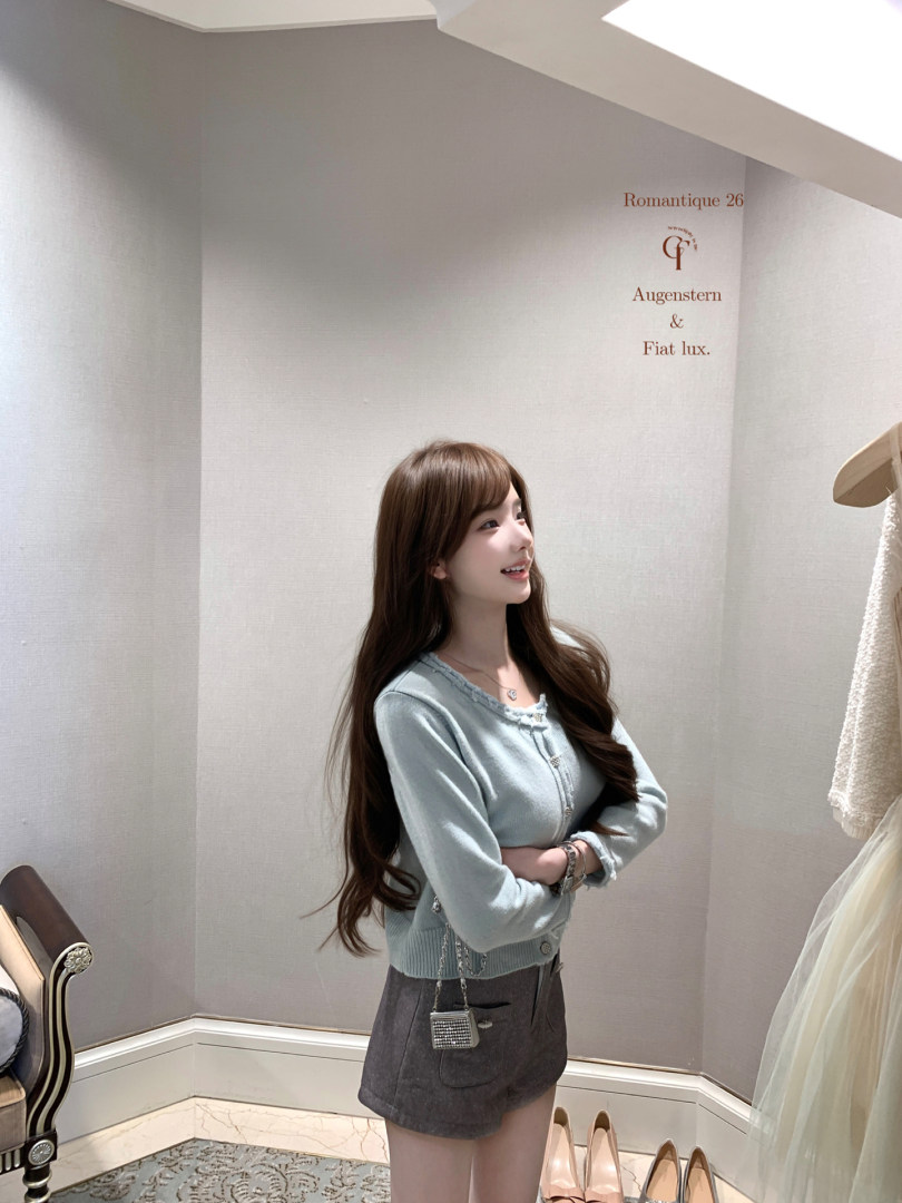 Woman wearing a light blue cardigan with a gray mini skirt in a boutique setting