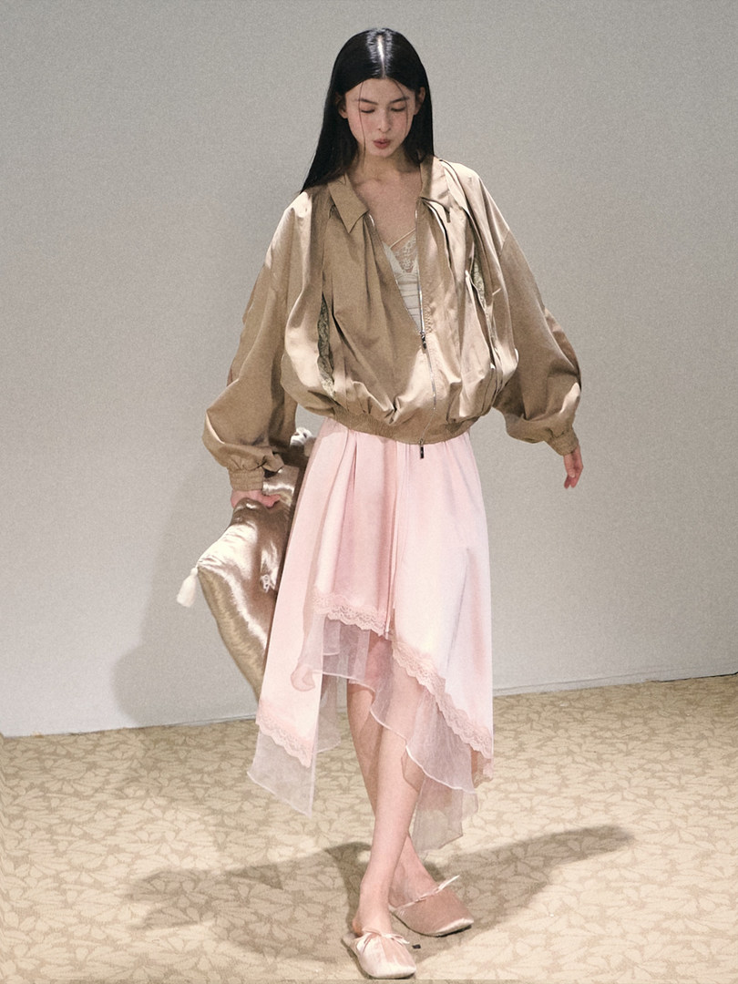 Model wearing a beige satin jacket with a pink sheer layered skirt and satin flats