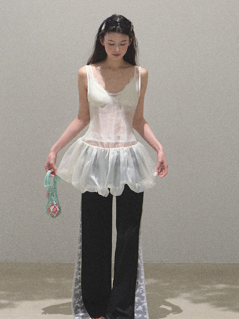 Model wearing a sheer white layered camisole top with black wide-leg pants