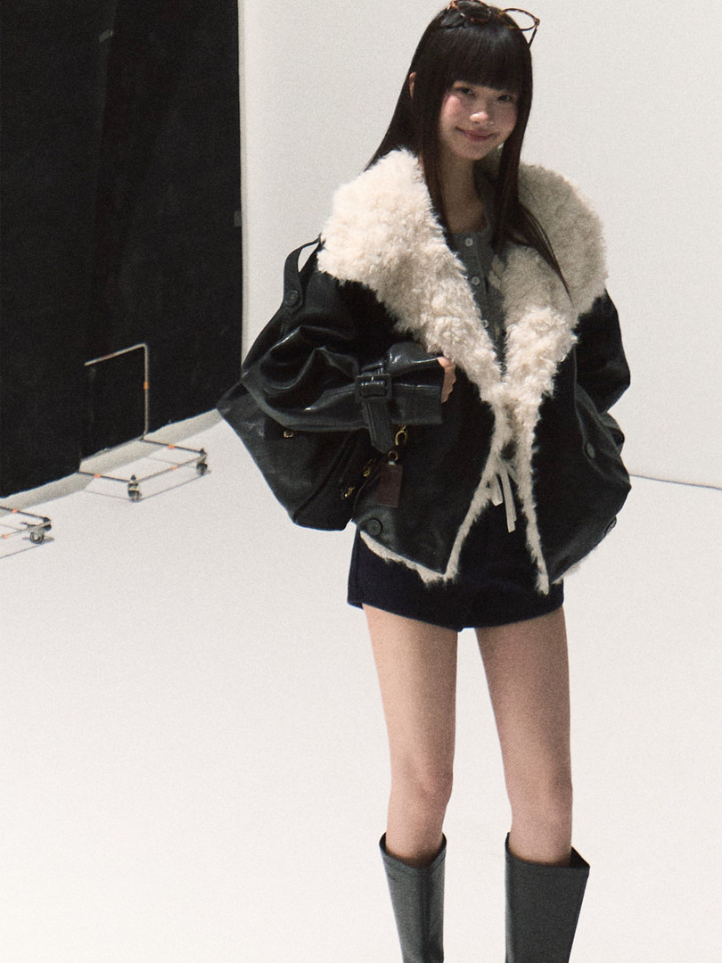 Model wearing a black shearling-lined jacket with tall boots