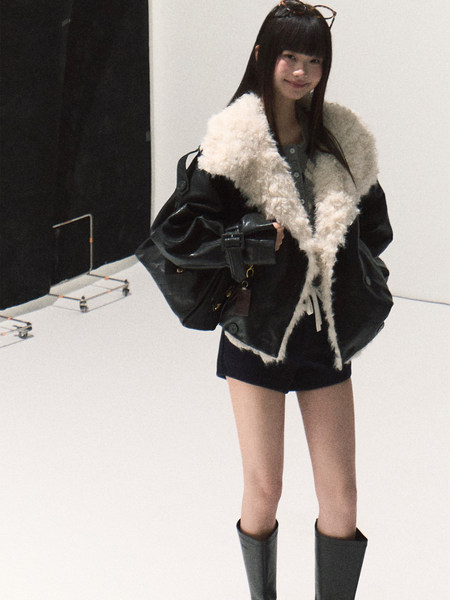 Model wearing a black shearling-lined jacket with tall boots