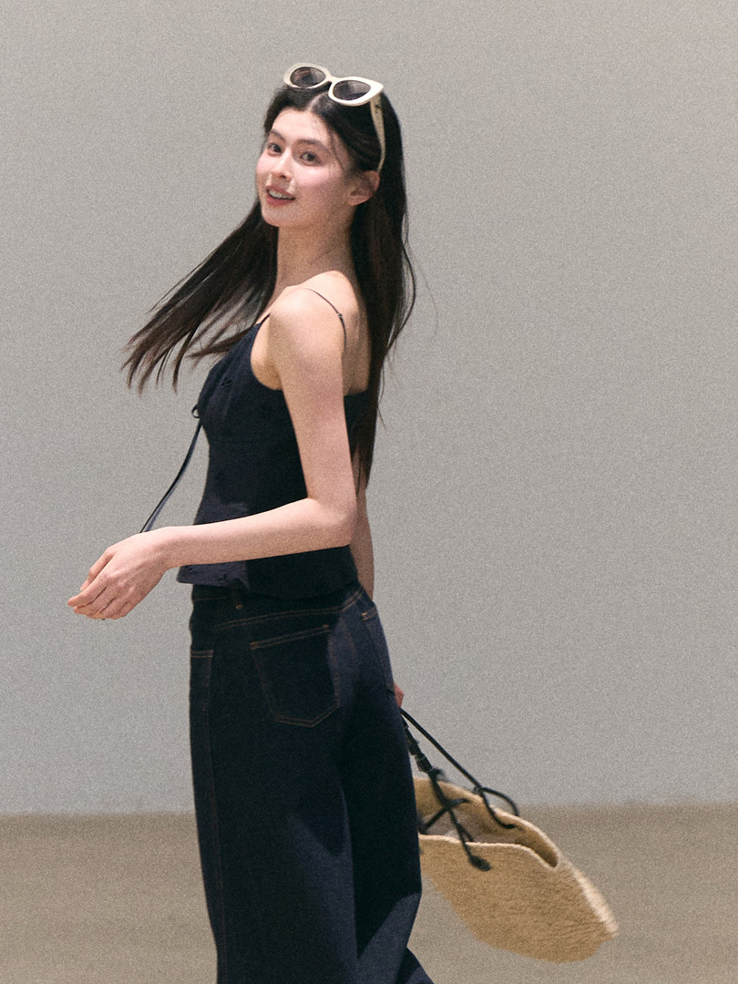 Woman modeling a black sleeveless top with dark jeans