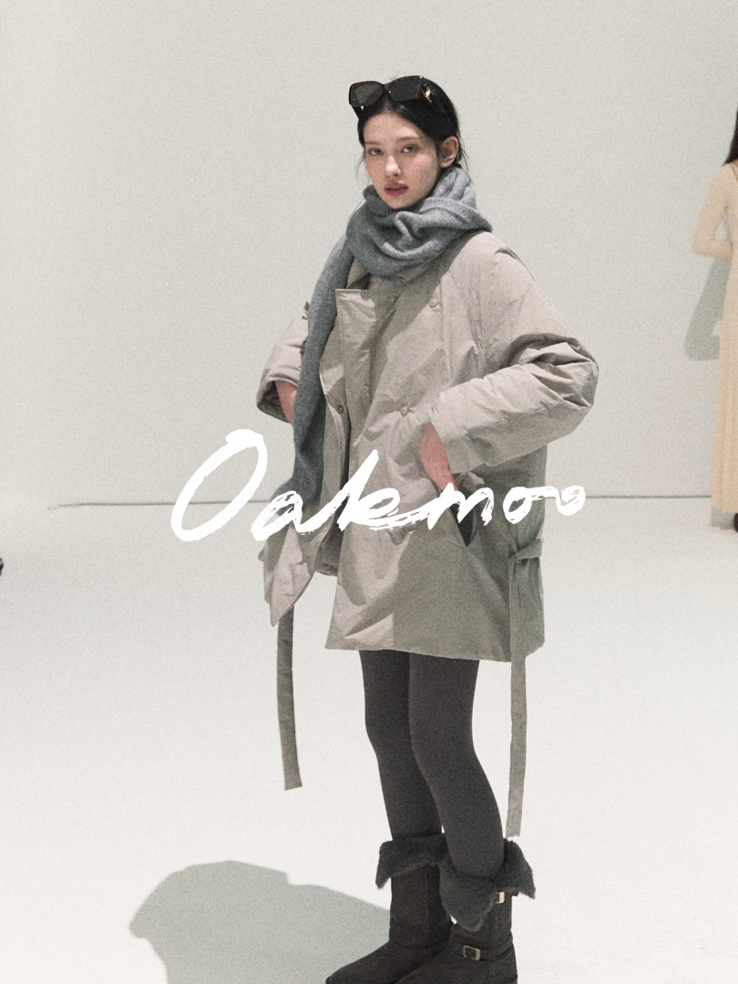 Model wearing an oversized gray coat with a matching scarf and black boots