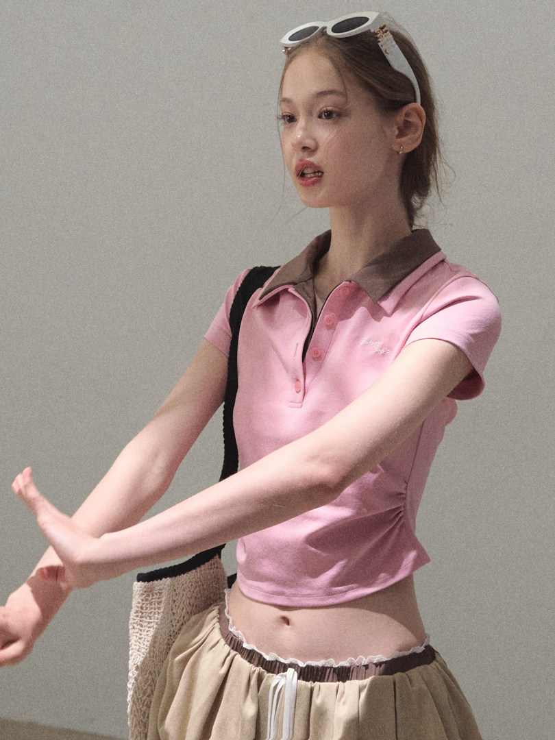 Model wearing a pink short-sleeve polo crop top with a brown collar