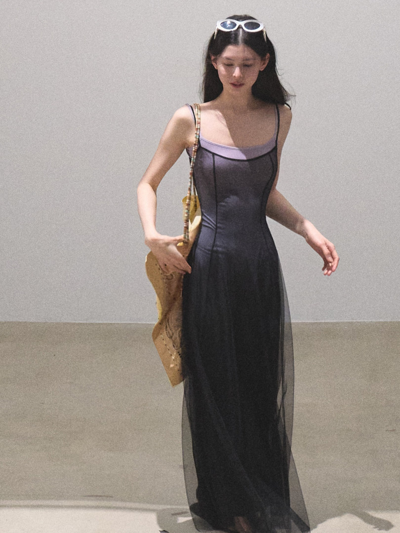 Woman wearing a black sheer slip dress with lavender trim and sunglasses