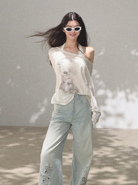 Model wearing a sheer white top, light blue jeans, and white sunglasses