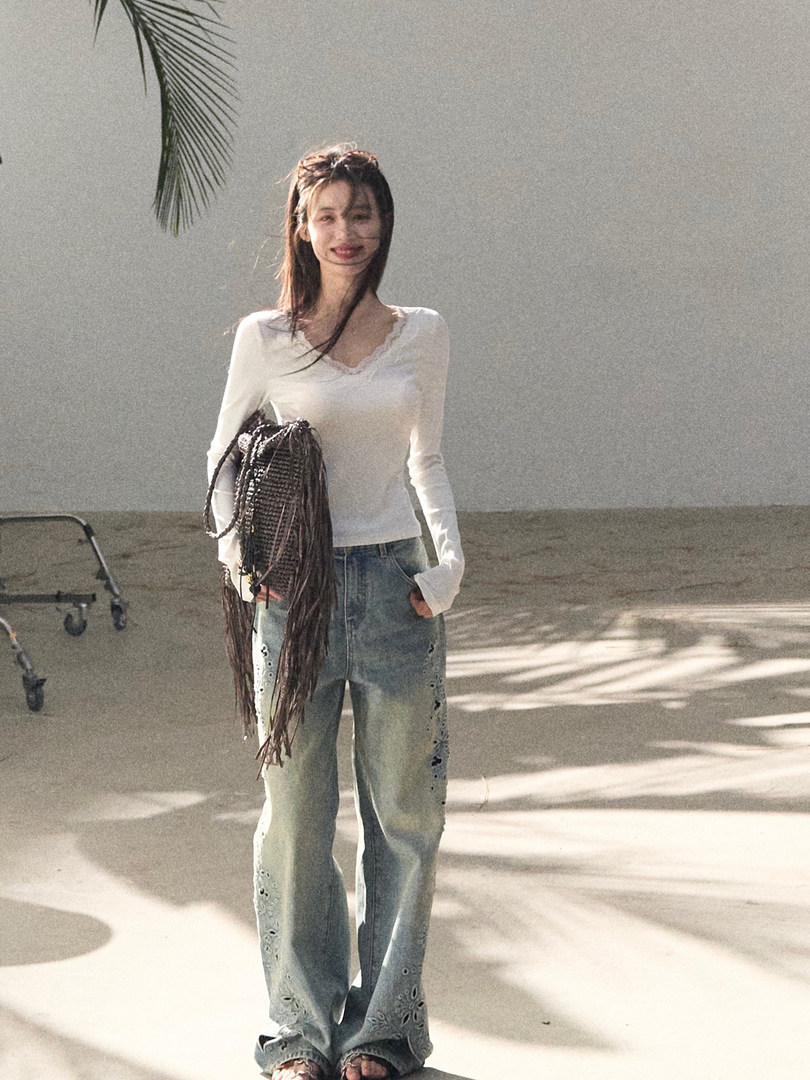 Woman wearing a white long-sleeve top and loose distressed jeans