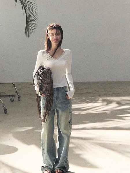 Woman wearing a white long-sleeve top and loose distressed jeans