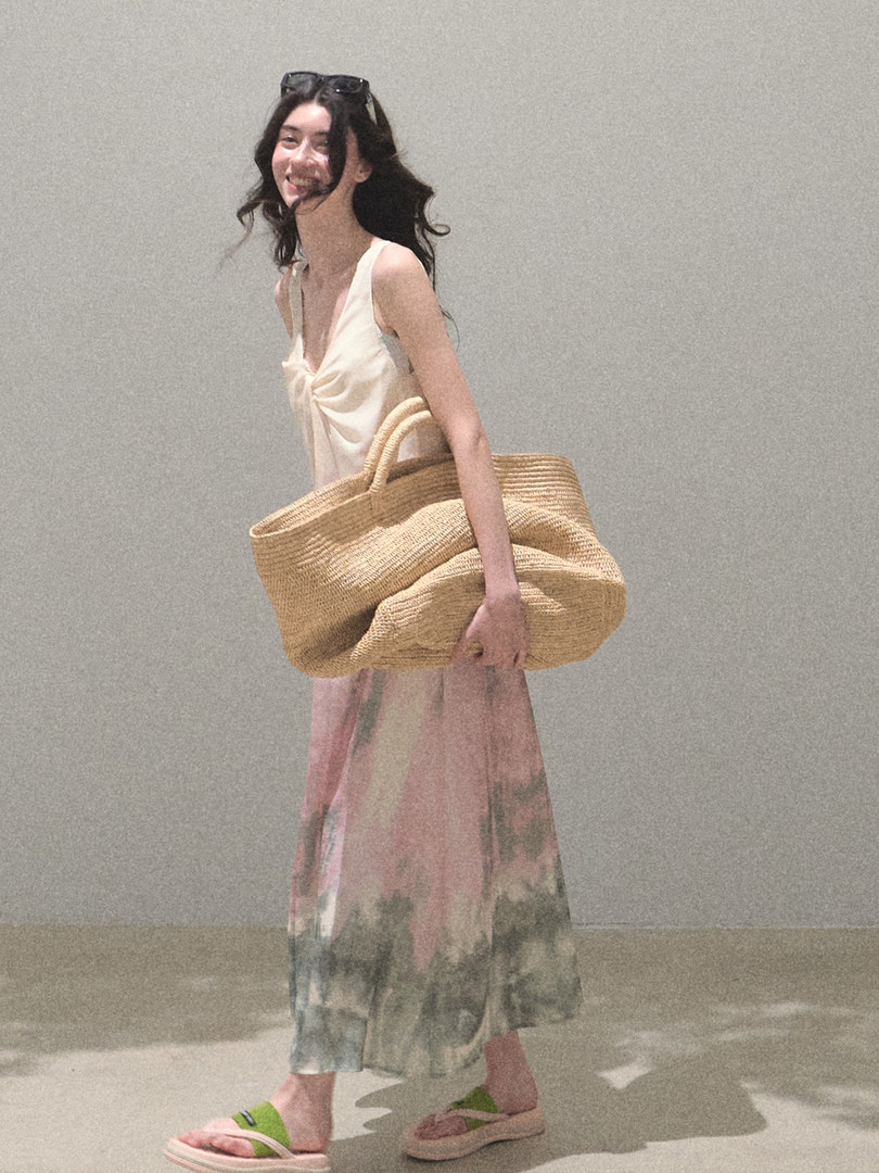 Woman wearing a light summer dress and carrying a large woven straw tote bag
