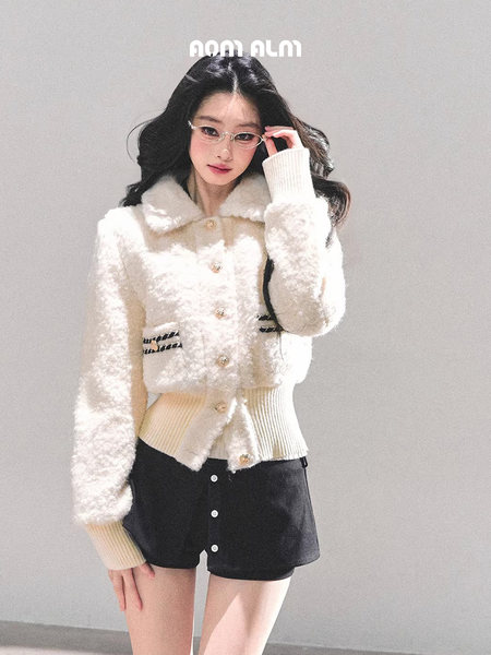 Model wearing a white fluffy cropped cardigan with black shorts