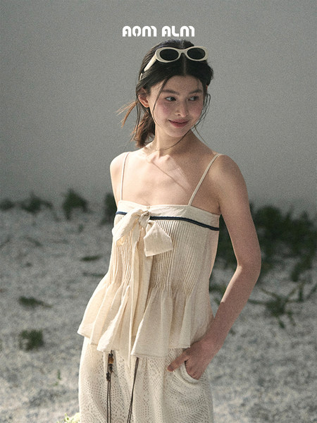 Woman modeling a beige summer beach outfit with spaghetti straps and a bow detail