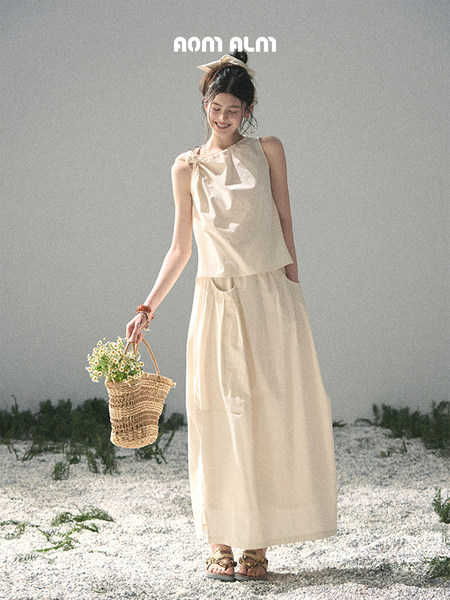 Cream sleeveless top and long skirt set worn by a model on a beach