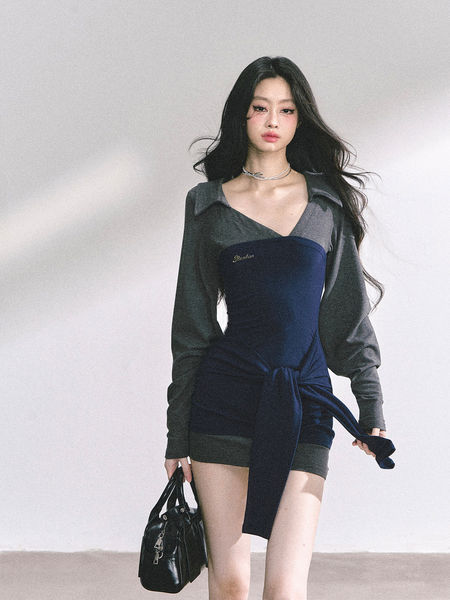 Model wearing a dark fitted long-sleeve mini dress with a layered wrap detail