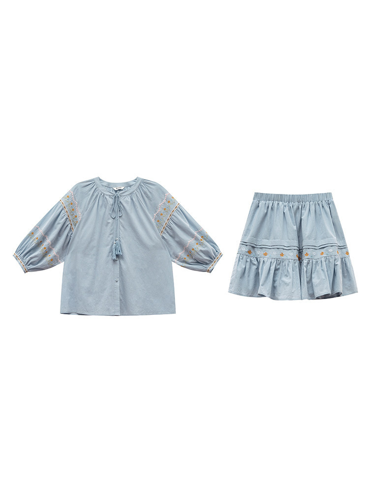 Light blue two-piece outfit set with a blouse and skirt laid flat on a white background