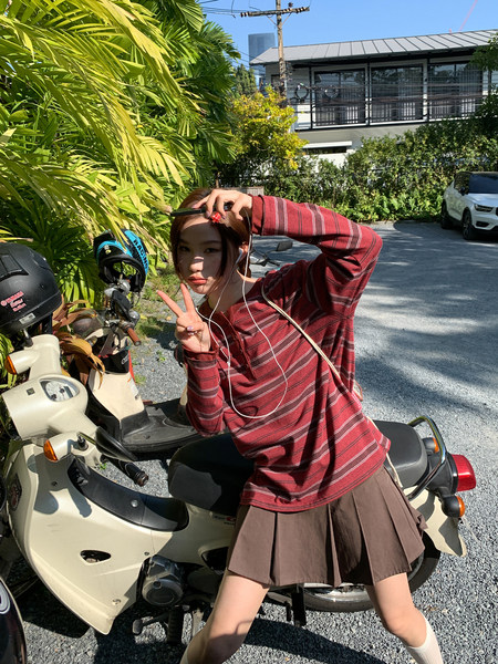 Person wearing a red striped long-sleeve top with a brown skirt outdoors